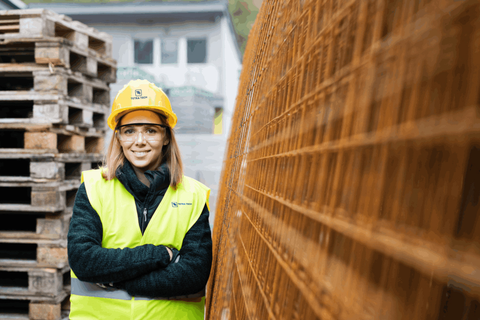 A person in construction gear standing next to palettes and other construction materials
