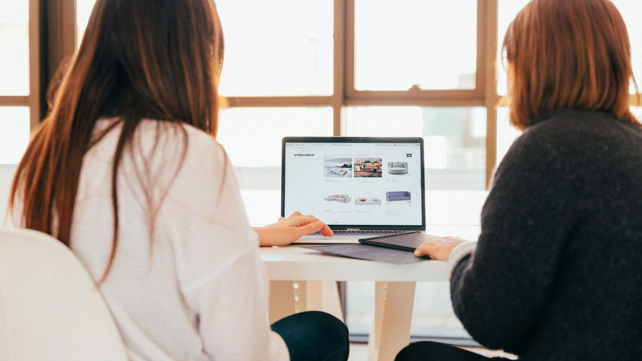 Two people looking at a laptop and taking notes