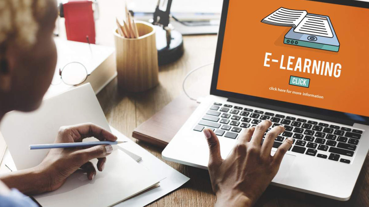 A person on a laptop with a screen open displaying text that reads "E-Learning, click here for more information"